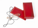 une petite boîte rouge sur laquelle est posée une paire de lunettes