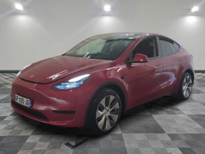 Le SUV Tesla rouge est garé dans le garage, sur un sol à damier.