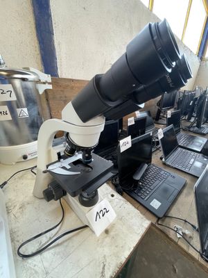 a microscope that is sitting on a table with laptops