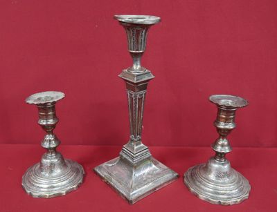 trois bougeoirs en argent sur fond rouge, avec un fond rouge