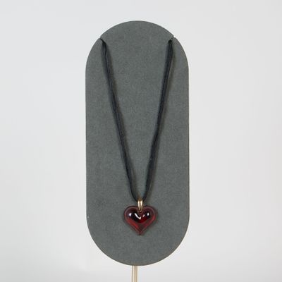 collier avec un cœur rouge sur un cordon noir, sur fond blanc