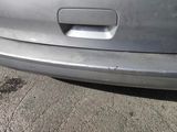 the rear end of a silver car is shown with rust on the ground