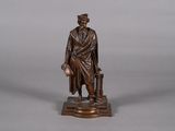 bronze statue of a man with a suitcase and a hat