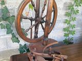 a spinning wheel on a wooden table with a plant in the background