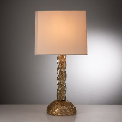 une image représentant une lampe dorée surmontée d'un abat-jour blanc