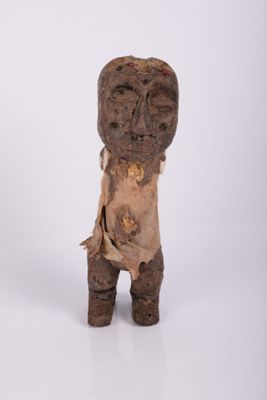 une vieille statue en bois représentant un homme debout sur une surface blanche