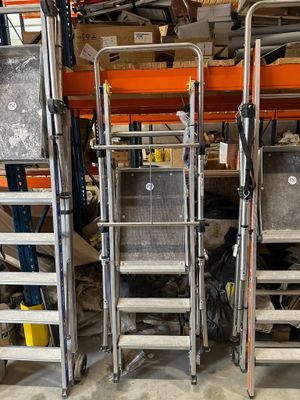 several ladders are stacked on top of each other in a warehouse