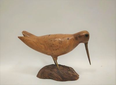 un petit oiseau en bois perché sur un rocher