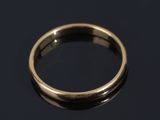 a close up of a gold wedding ring on a black surface
