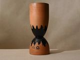 un vase marron orné d'un motif noir, posé sur une table