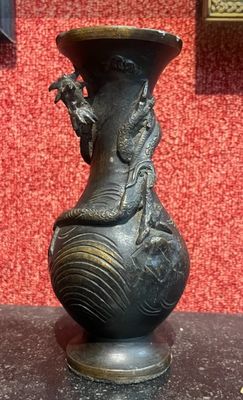 un vase noir orné d'un dragon, posé sur une table