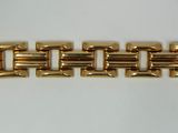 a close up of a gold bracelet on a white surface