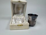 une tasse en argent posée à côté d'une tasse en argent dans une boîte