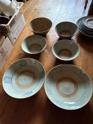 Plusieurs bols et assiettes sont posés sur une table en bois.