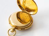 a gold pocket watch sitting on a white surface