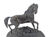 bronze statue of a horse running on a rock on a white background