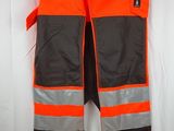 un gilet de sécurité orange et noir accroché au mur