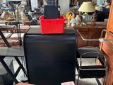 a black refrigerator sitting in a room with a red box on top of it