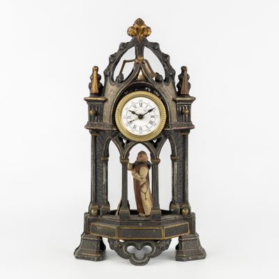 a clock with a statue on top of it on a table