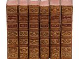 six vieux livres sont alignés sur une surface blanche