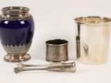 a blue vase, a silver cup, and a spoon on a white surface