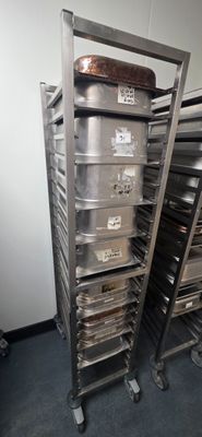 several trays of food are stacked on a metal rack in a kitchen