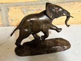 a bronze statue of an elephant holding a fish in its mouth