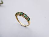a close up of a gold ring with emerald stones