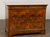 une commode ancienne avec un plateau en marbre, posée sur un sol carrelé