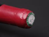 a close up of a red wine bottle with a green cap