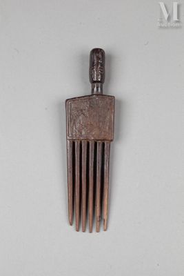 un petit peigne en bois sur lequel est représenté un visage
