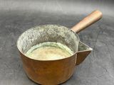 a metal pan with a wooden handle on a table