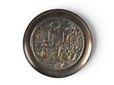 a silver plate with a picture on it on a white surface