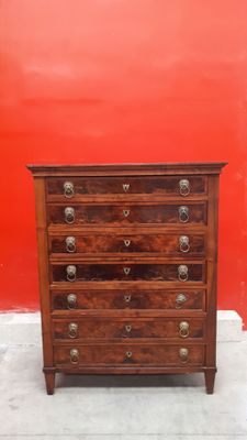 une commode en bois adossée à un mur rouge