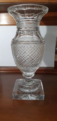 a glass vase sitting on a wooden table next to a mirror