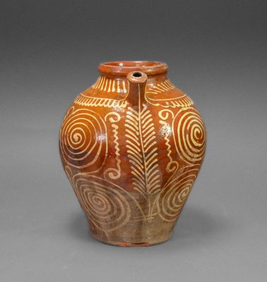a brown vase with white designs on it on a gray surface