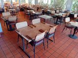de nombreuses tables et chaises dans un restaurant donnant sur l'extérieur