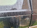 a close up of a dirty car door with water on it