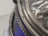 a blue glass vase with a silver lid on a table
