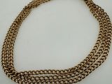 a close up of a gold chain necklace on a white surface