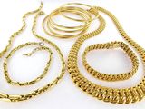 plusieurs bijoux en or posés sur une surface blanche