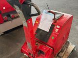 une machine rouge posée sur une palette dans un parking