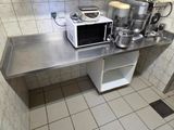 une petite cuisine avec un micro-ondes posé sur le plan de travail