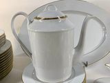 a lot of white and gold plates and cups on the table