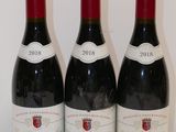 trois bouteilles de vin rouge sont alignées sur une table