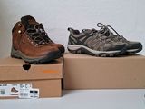 deux paires de chaussures de randonnée posées sur des cartons, sur une table