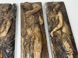 three wooden sculptures of a woman and a man on a white surface