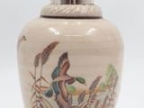 un petit vase avec un oiseau sur une surface blanche