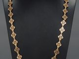 a gold necklace on a mannequin with a black background