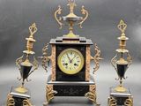 a clock that is sitting on a table next to three vases